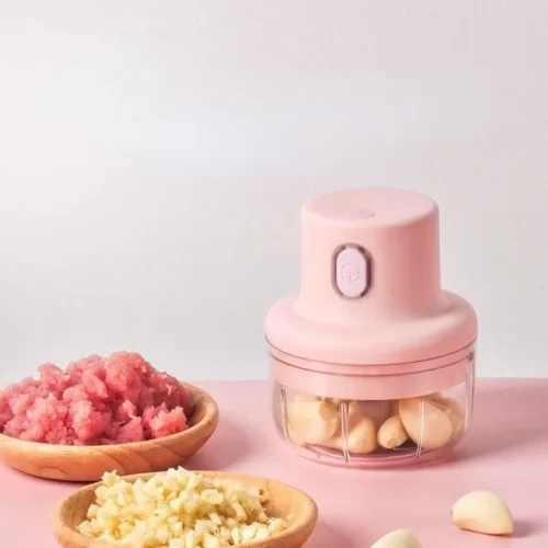 Mini electric garlic chopper with garlic cloves in the bowl